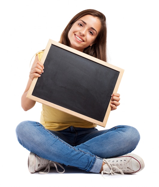 Estudiante con las piernas cruzadas enseñando una pizarra