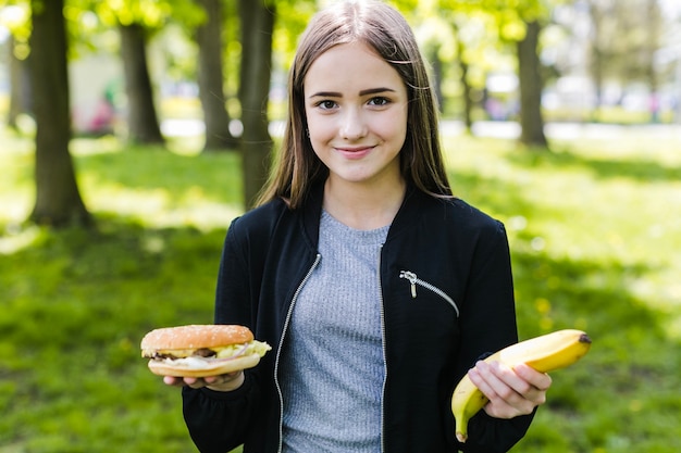 Foto gratuita estudiante posando con plátano y hamburguesa