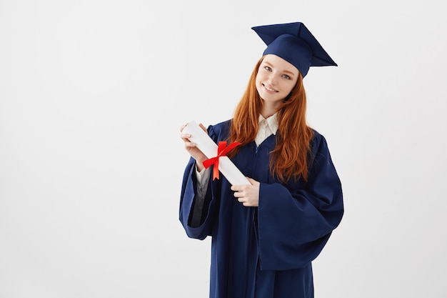 Estudiante de posgrado pelirroja femenina con diploma sonriendo. Copyspace