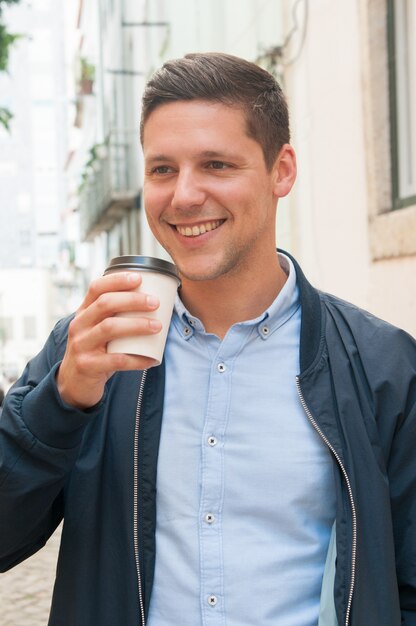 Estudiante positivo feliz bebiendo café para llevar