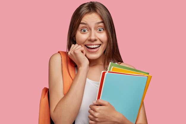 Estudiante positivo posando contra la pared rosa