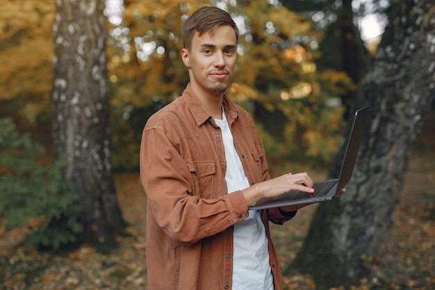 Estudiante que trabaja en un parque y usa la computadora portátil