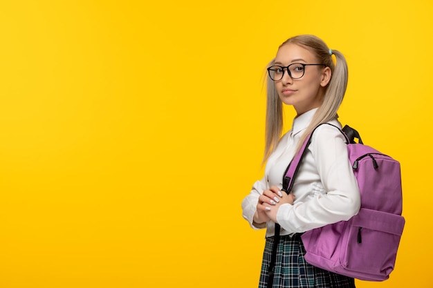 Estudiante rubia del día mundial del libro con colas de caballo y gafas sobre fondo amarillo