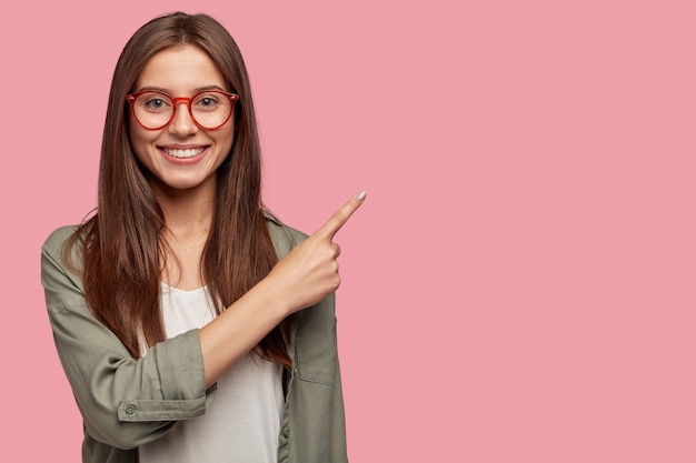 Estudiante satisfecho posando contra la pared rosa