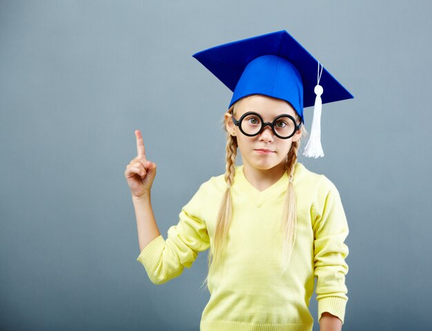 Estudiante señalando hacia arriba con gorro de graduación