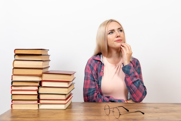 estudiante sentada con libros pensando en blanco