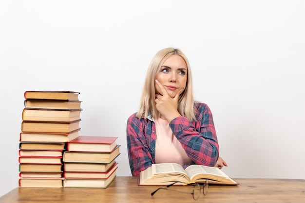 estudiante sentada con libros y pensando en blanco