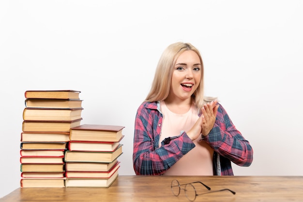 Estudiante sentada con libros y posando aplaudiendo en blanco