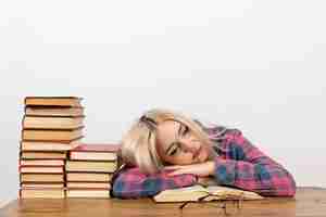 Foto gratuita estudiante sentada con libros sintiéndose cansada y durmiendo en blanco