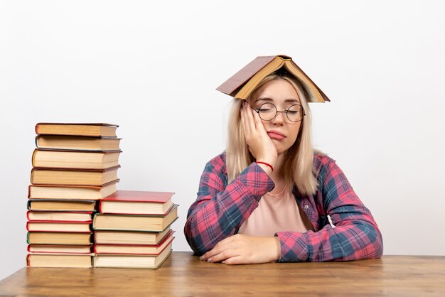 Estudiante sentada con libros sosteniendo uno sobre su cabeza en blanco