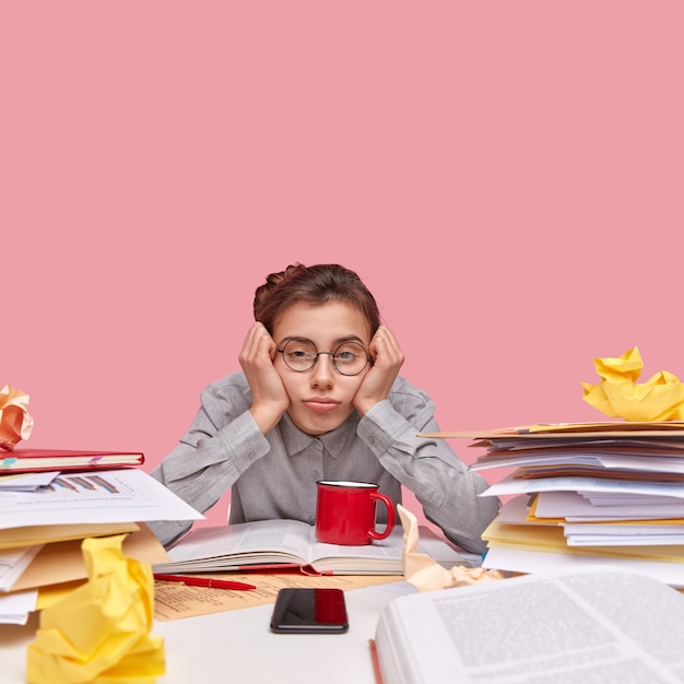 Estudiante sentado en un escritorio lleno de libros