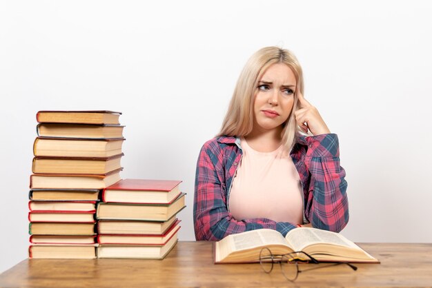 Estudiante sentado con libros y posando en blanco