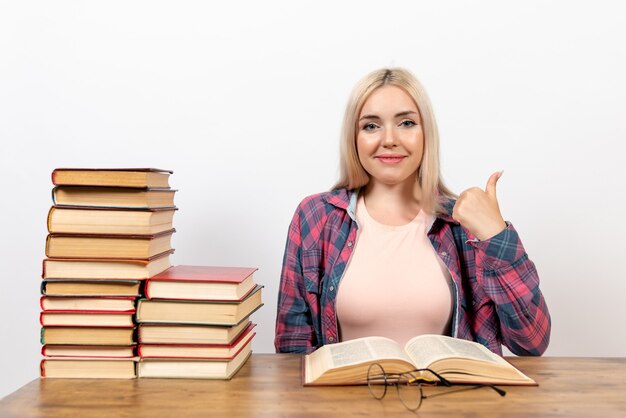 Estudiante sentado con libros y posando en blanco