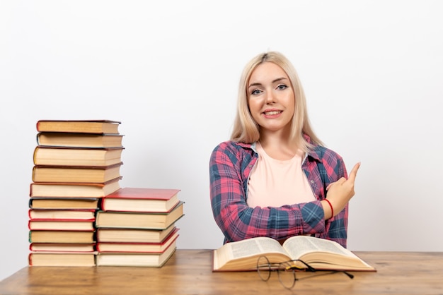 Estudiante sentado con libros y posando en blanco