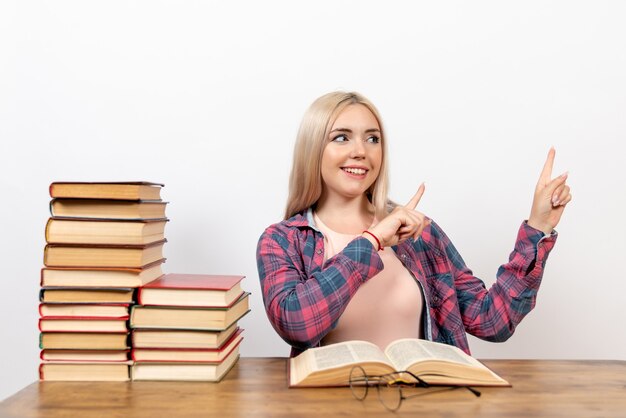 Estudiante sentado con libros y posando en blanco