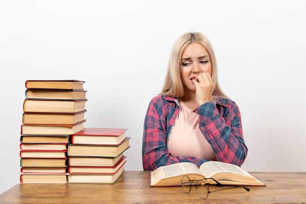 Estudiante sentado con libros y posando en blanco