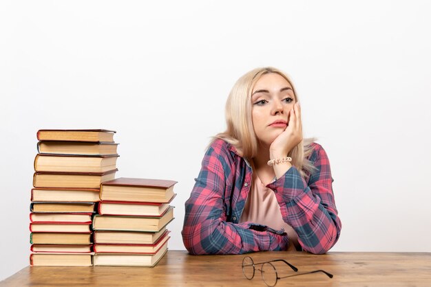 Estudiante sentado con libros y posando en blanco