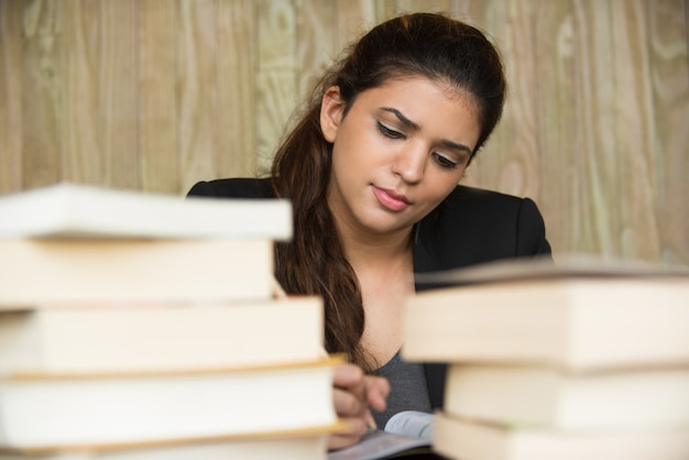 Foto gratuita estudiante serio escribiendo entre los libros de texto