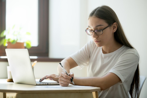 Estudiante serio que trabaja en la computadora portátil que se prepara para los exámenes