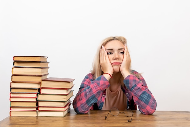 Estudiante solo sentada con diferentes libros cansado en blanco