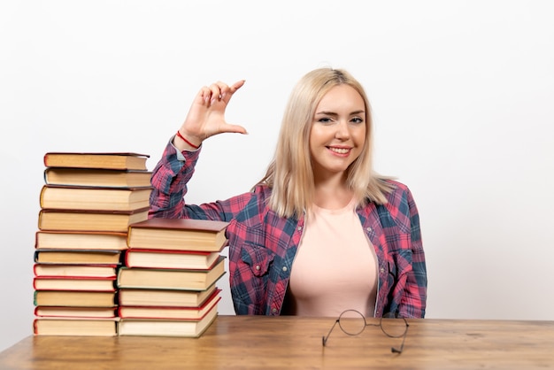 Estudiante solo sentada con diferentes libros sonriendo en blanco