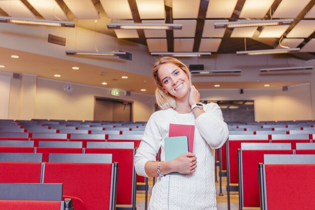 Estudiante sonriente con cuadernos en el hall