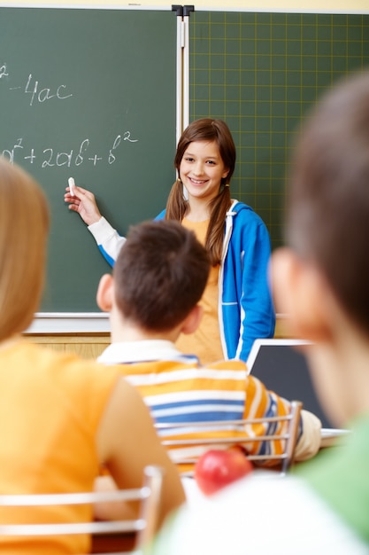 Foto gratuita estudiante sonriente escribiendo matemáticas en la pizarra