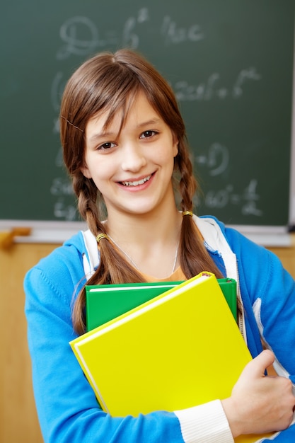 Estudiante sonriente con la pizarra de fondo