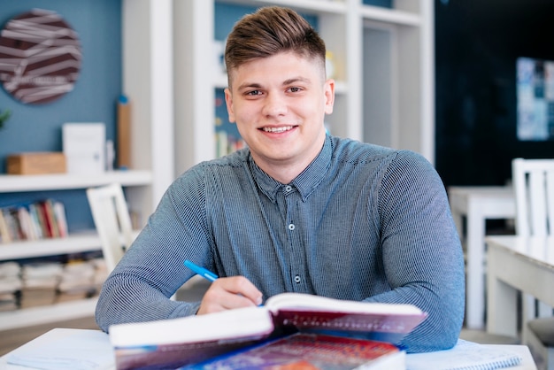 Estudiante sonriente que estudia en biblioteca