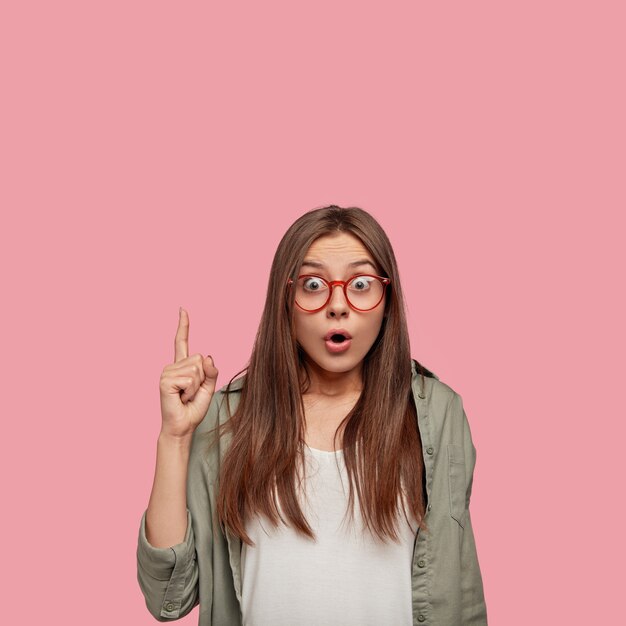 estudiante sorprendido posando contra la pared rosa