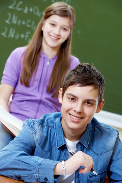 Estudiante sosteniendo un bolígrafo con la compañera de fondo