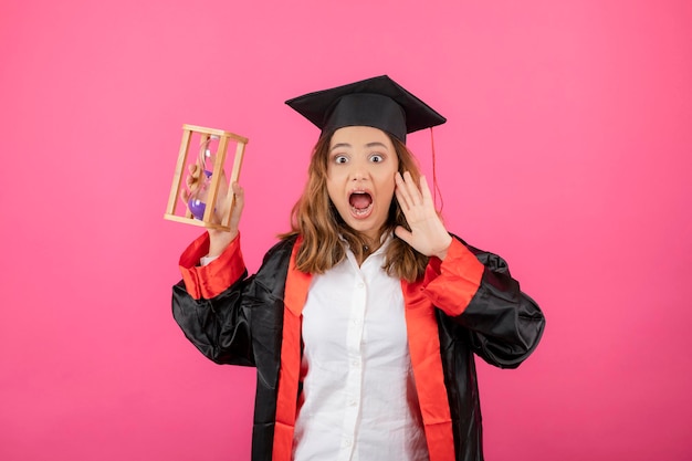 Una estudiante sosteniendo un reloj de arena y gritando. foto de alta calidad