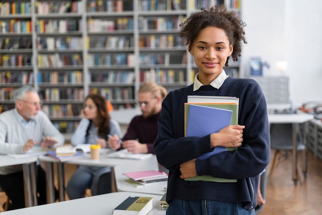 Estudiante de tiro medio sosteniendo libros