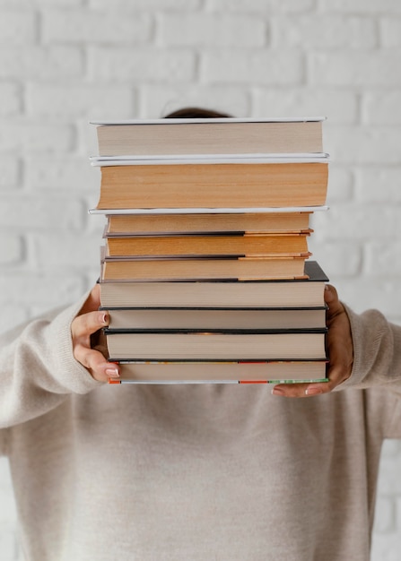 Estudiante de tiro medio sosteniendo la pila de libros