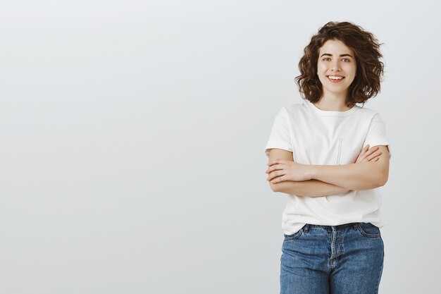 Estudiante universitaria feliz confidente sonriendo con las manos cruzadas