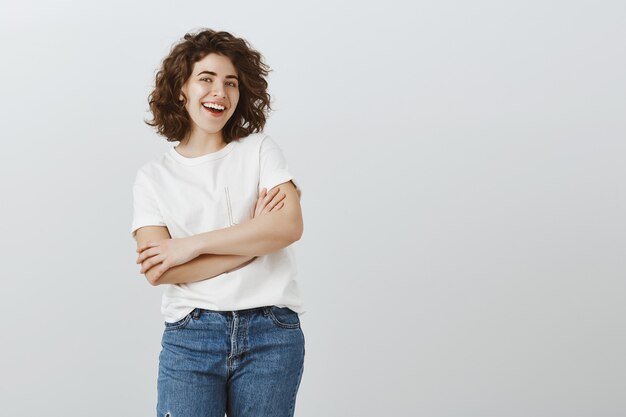 Estudiante universitaria feliz confidente sonriendo con las manos cruzadas