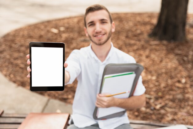 Estudiante universitaria mostrando su tableta y sosteniendo una carpeta
