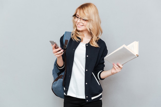 Estudiante usando el teléfono y sosteniendo el libro