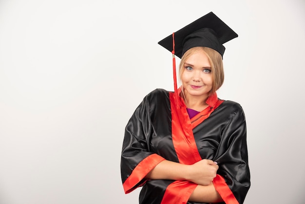 Estudiante en vestido de pie sobre fondo blanco. Foto de alta calidad