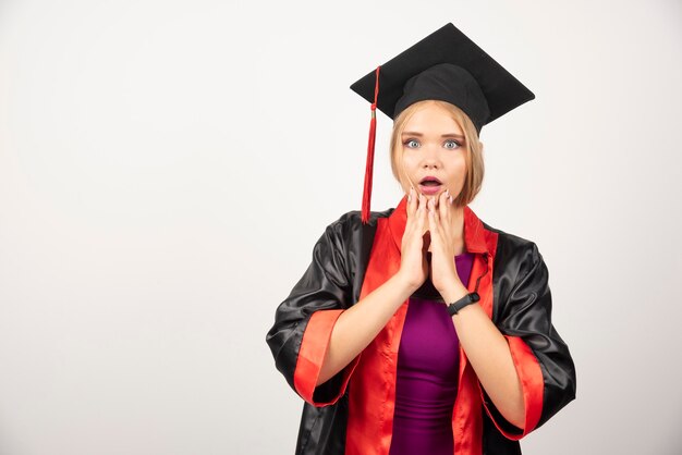 Estudiante en vestido sosteniendo su rostro en blanco.