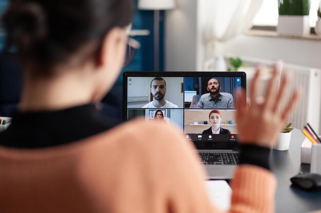 Estudiante en una videollamada grupal en una laptop. Freelancer trabajando desde la oficina en casa reuniéndose con colegas en línea. Colega saludando a la pantalla en la conferencia del equipo de cámaras web. Conversación informativa remota.