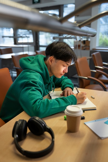 Foto gratuita estudiante de vista lateral escribiendo en el cuaderno