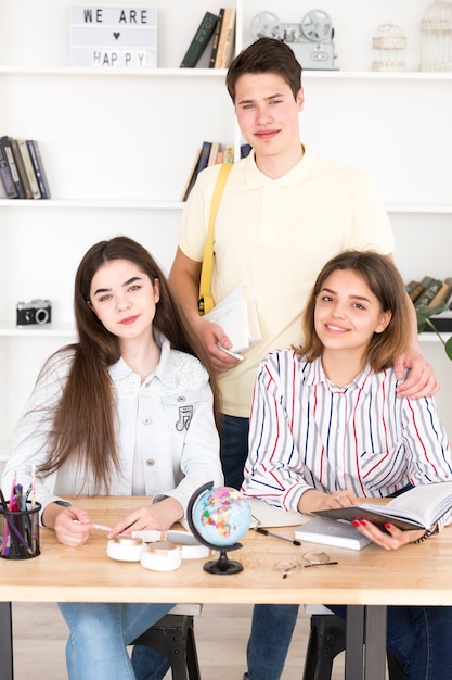 Estudiantes adolescentes estudiando en la mesa y mirando a la cámara