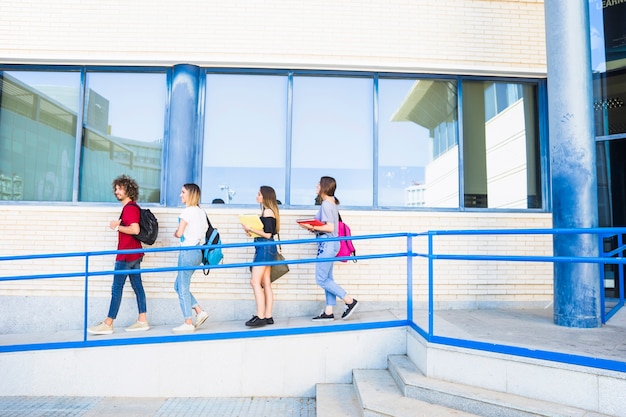 Foto gratuita estudiantes caminando en la rampa cerca de la construcción de la universidad