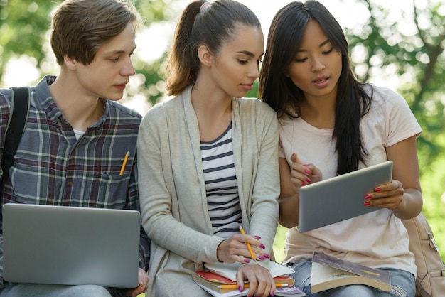 Estudiantes concentrados sentados y estudiando al aire libre