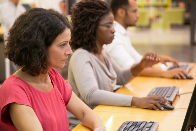 Estudiantes enfocados trabajando con computadoras en la biblioteca