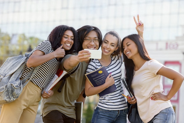 Foto gratuita estudiantes felices de pie y hacer selfie al aire libre