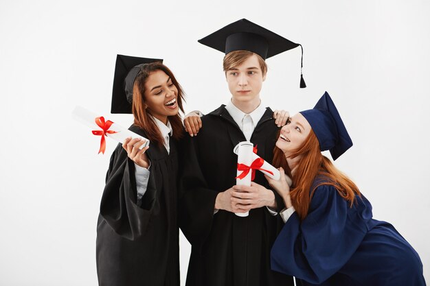 Estudiantes internacionales graduados regocijándose sonriendo posando.