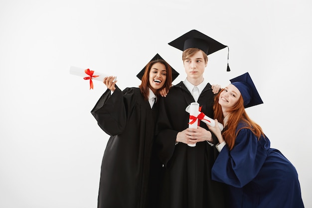 Estudiantes internacionales graduados regocijándose sonriendo posando.