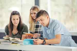 Foto gratuita estudiantes con libros en la mesa juntos